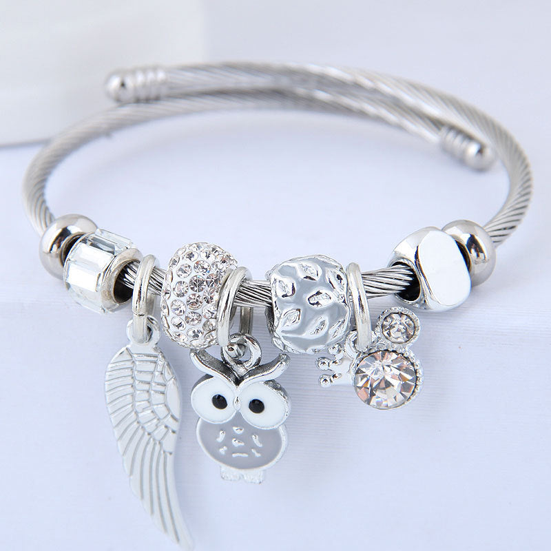 Bracelet en acier inoxydable orné d'un pendentif de chouette et d'ailes d'ange.