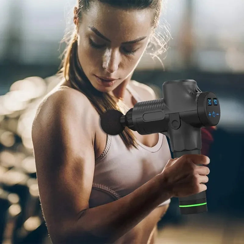 Femme utilisant un pistolet de massage musculaire noir sur l'épaule après l'entraînement