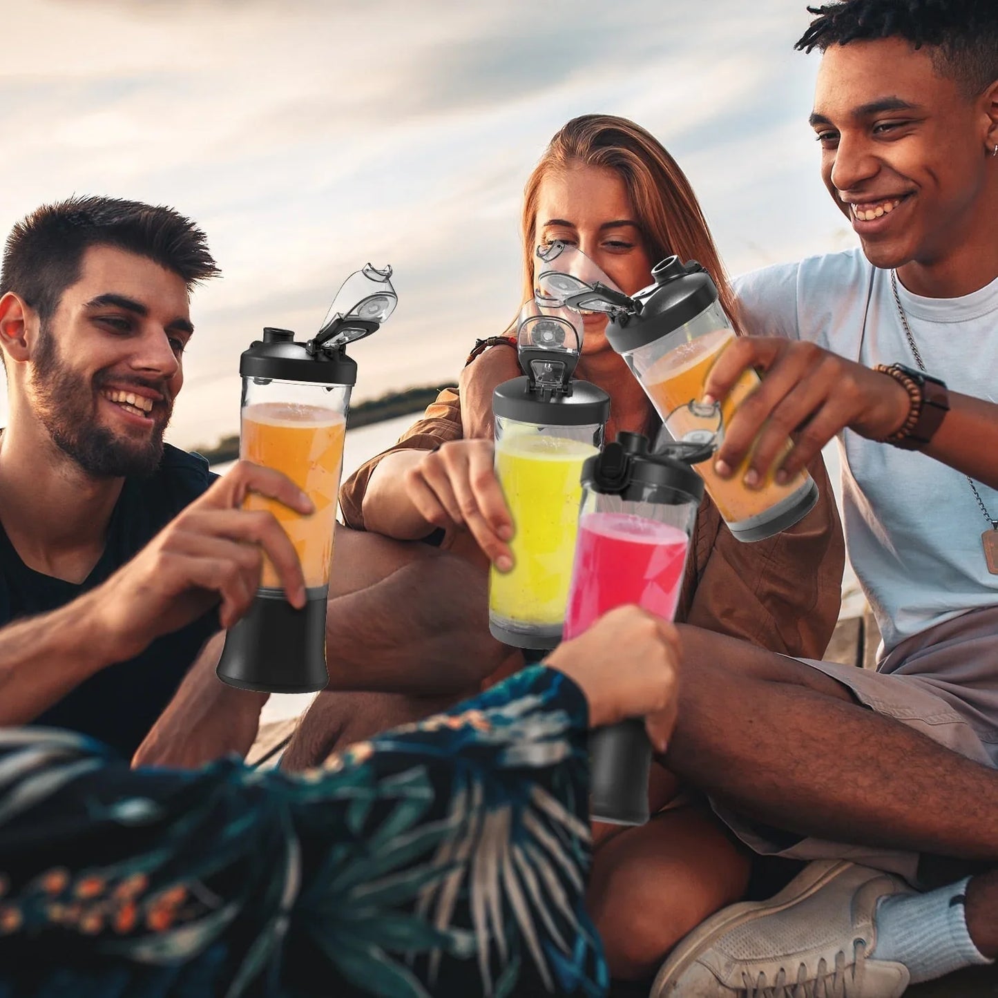 Groupe d'amis trinquant avec des gourdes isothermes colorées en plein air